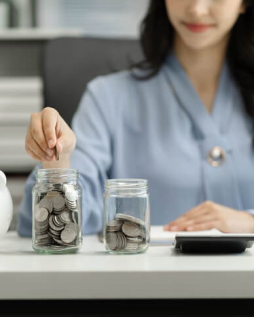 businesswoman hand puting coins in glass for saving money. concept finance and accounting in the home.